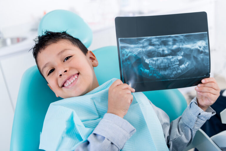Happy boy at the dentist holding an x-ray